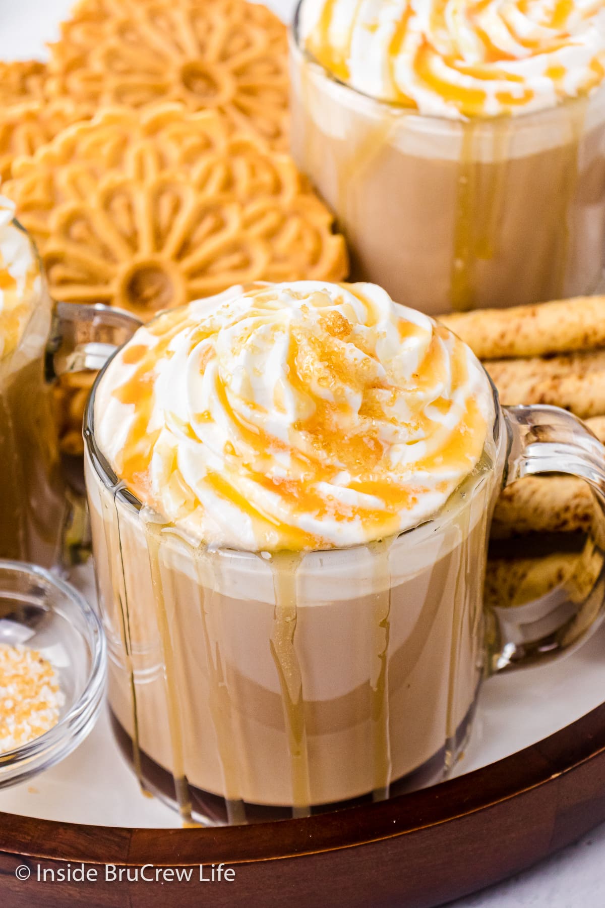 A tray of cookies and two lattes with whipped cream.