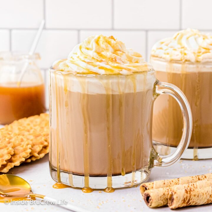 A clear cup filled with a homemade caramel latte with whipped topping and drizzles.