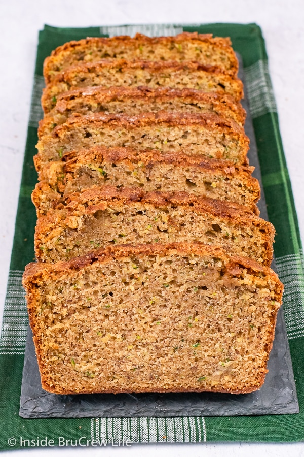 Slices of zucchini bread laying on a green towel.
