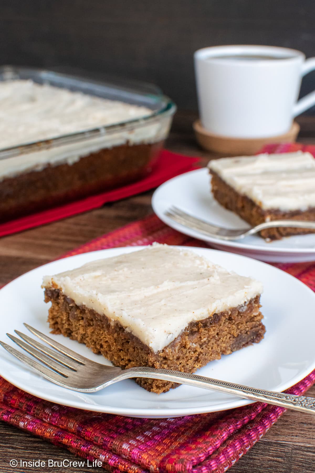 Slices of frosted apple butter cake on white plates.