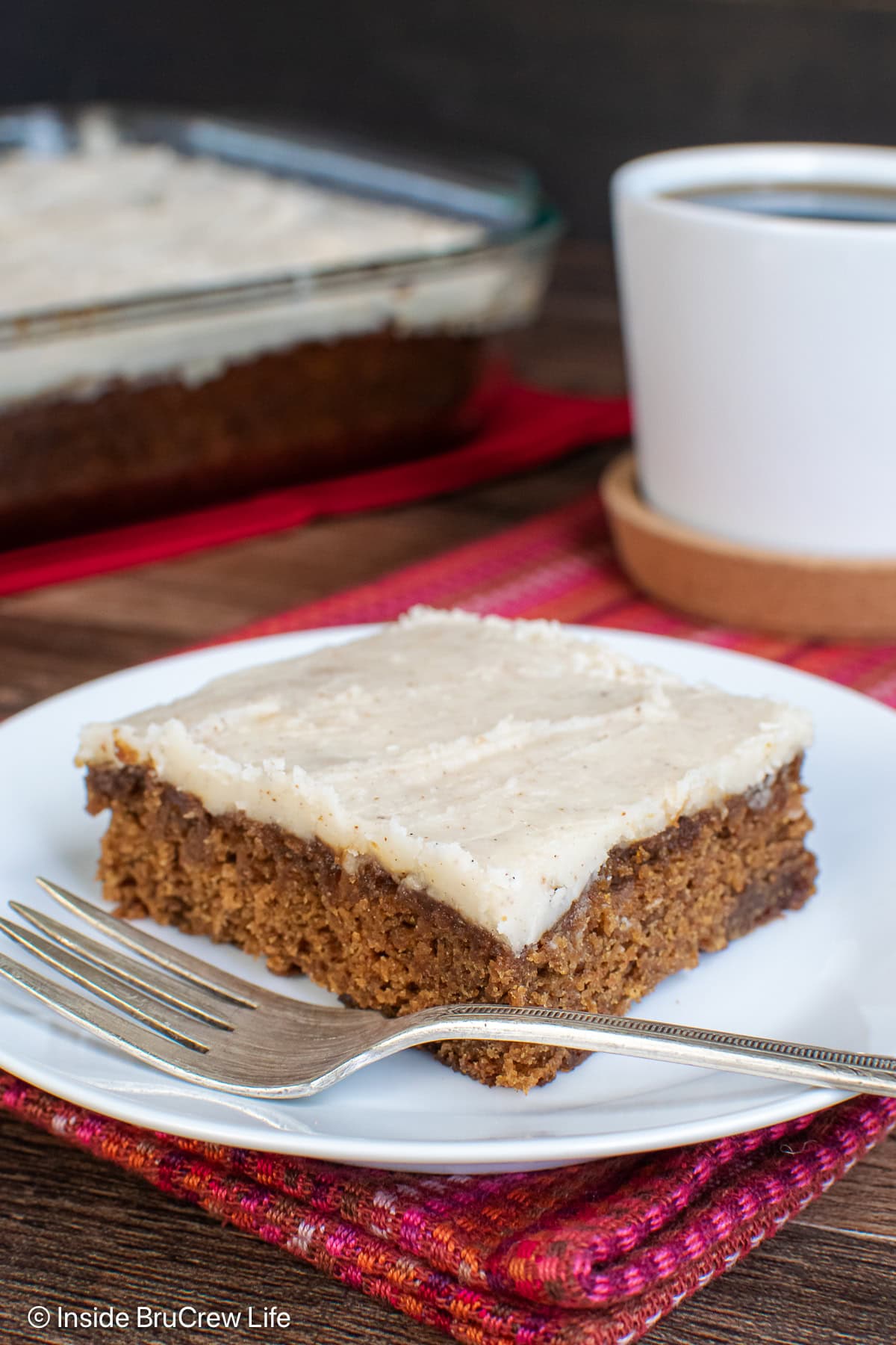 A slice of glazed apple spice cake on a white plate.