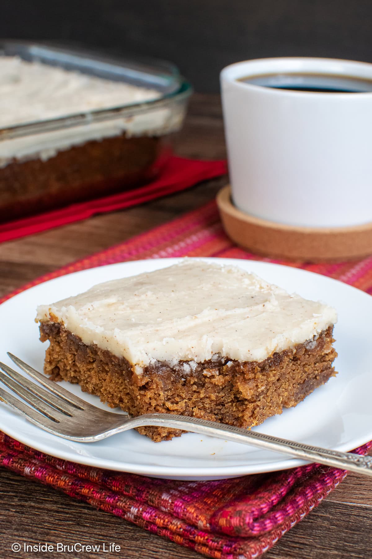 A square of apple butter cake on a plate with a piece missing.