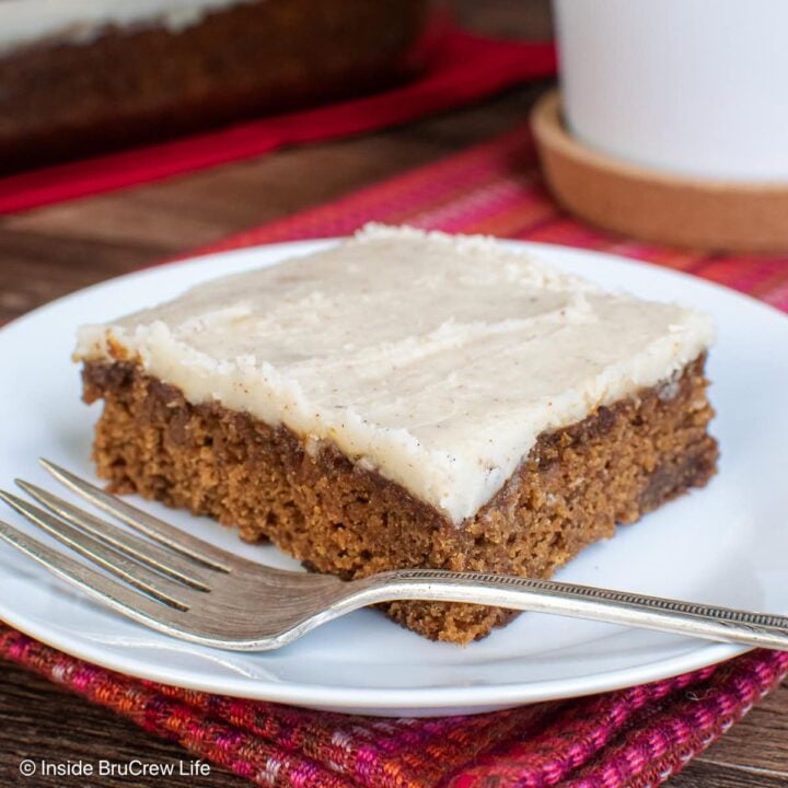 A slice of glazed apple spice cake on a white plate.