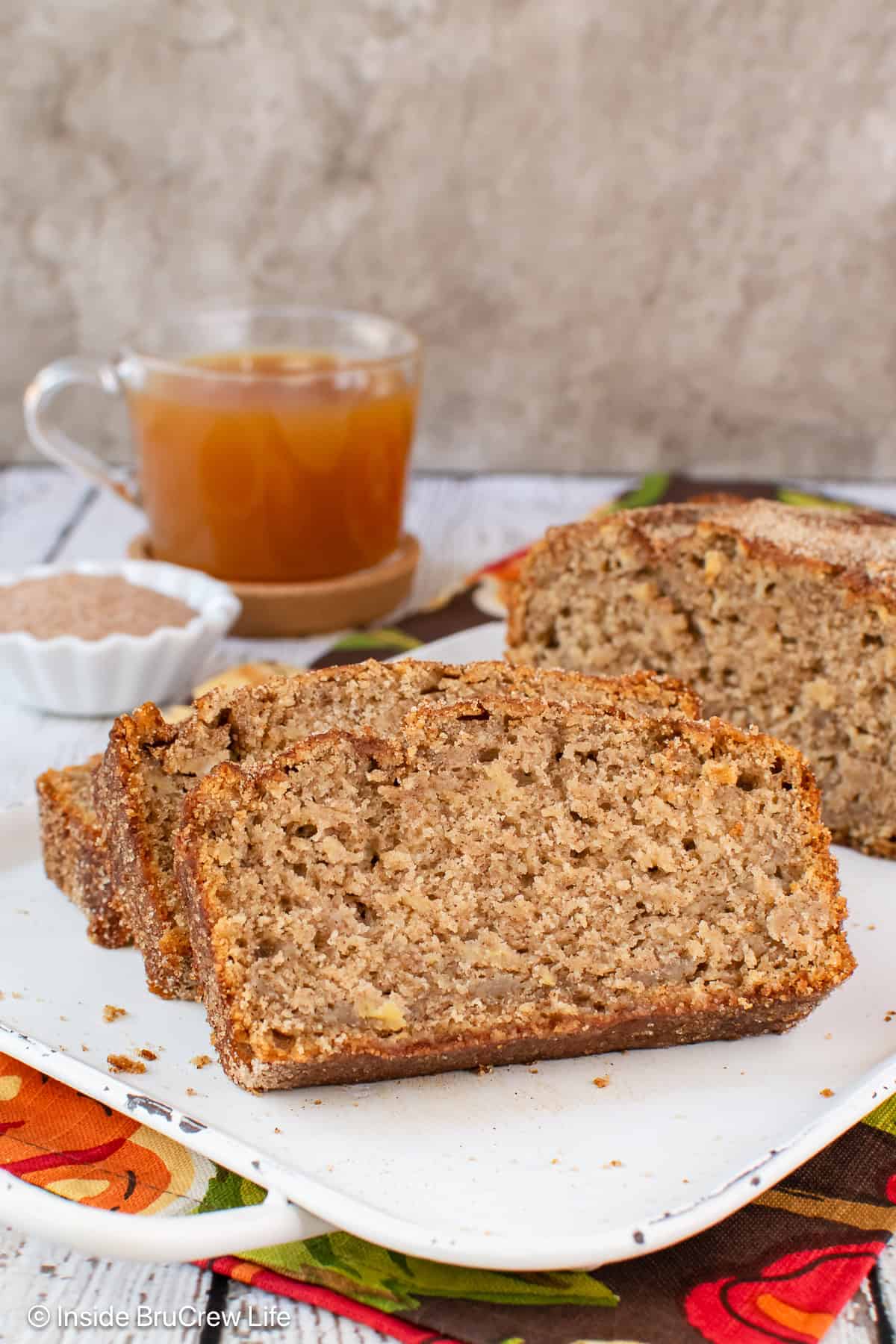 Slices of apple cider bread with cinnamon sugar laying on a white tray.