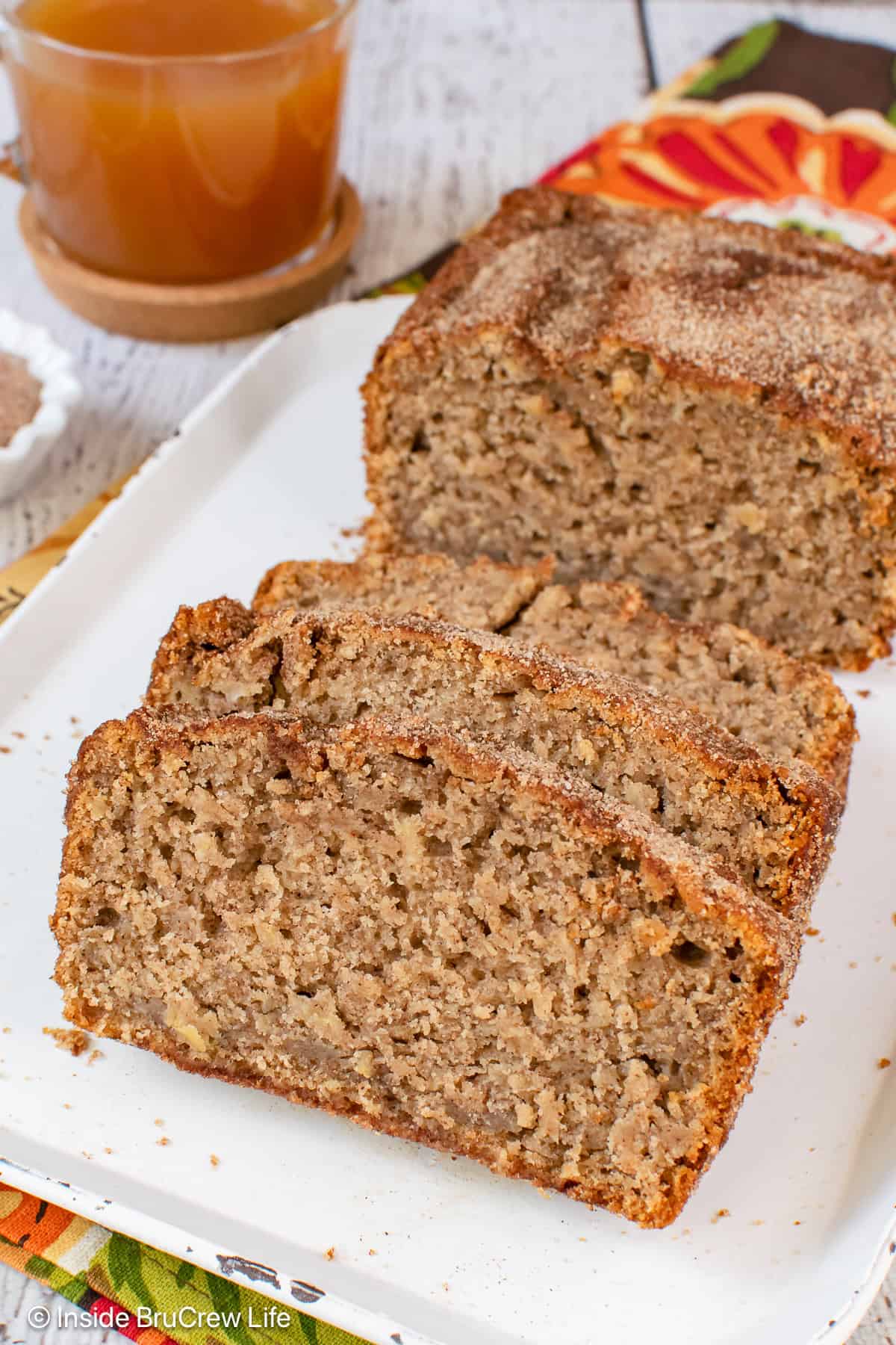 A white tray with slices of apple cider bread and the rest of the loaf on it.
