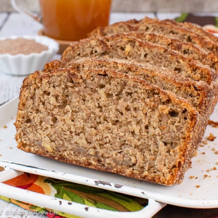 An apple cider bread cut into slices and stacked on a white tray.