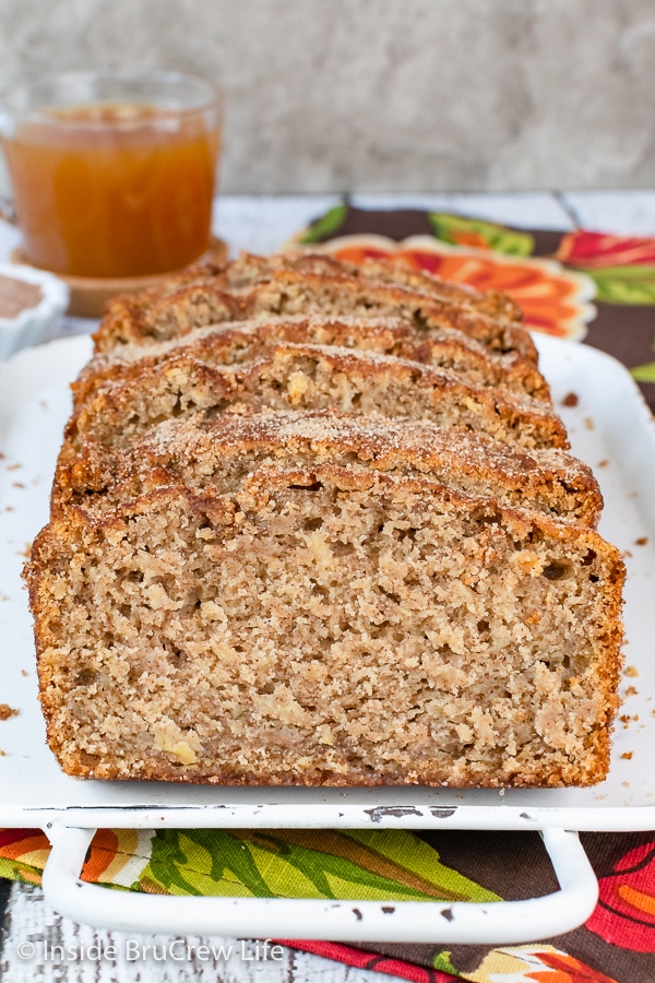 Slices of cinnamon sugar topped apple cider bread on a white tray.