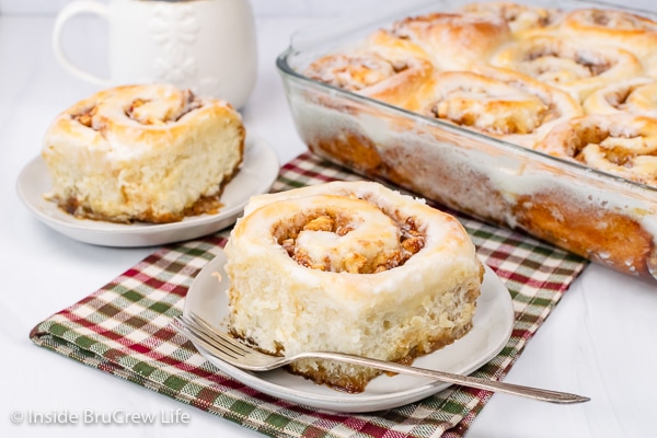 Two white plates with homemade apple cinnamon rolls on them.