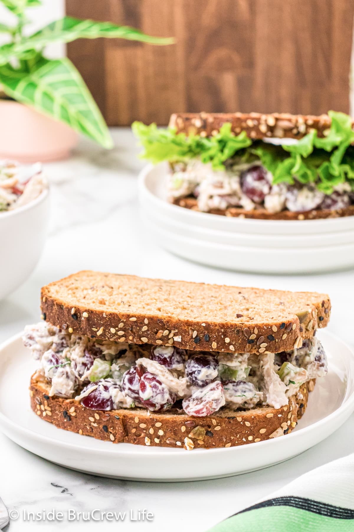 A chicken salad sandwich on a white plate.