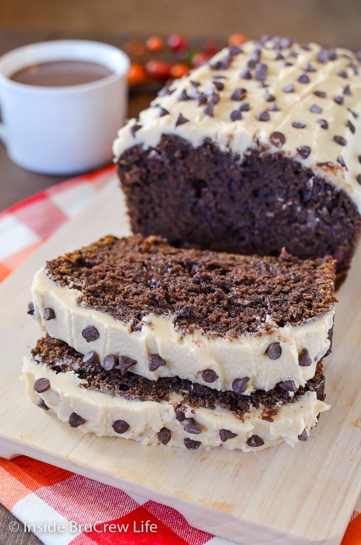 Slices of frosted chocolate bread on a cutting board.