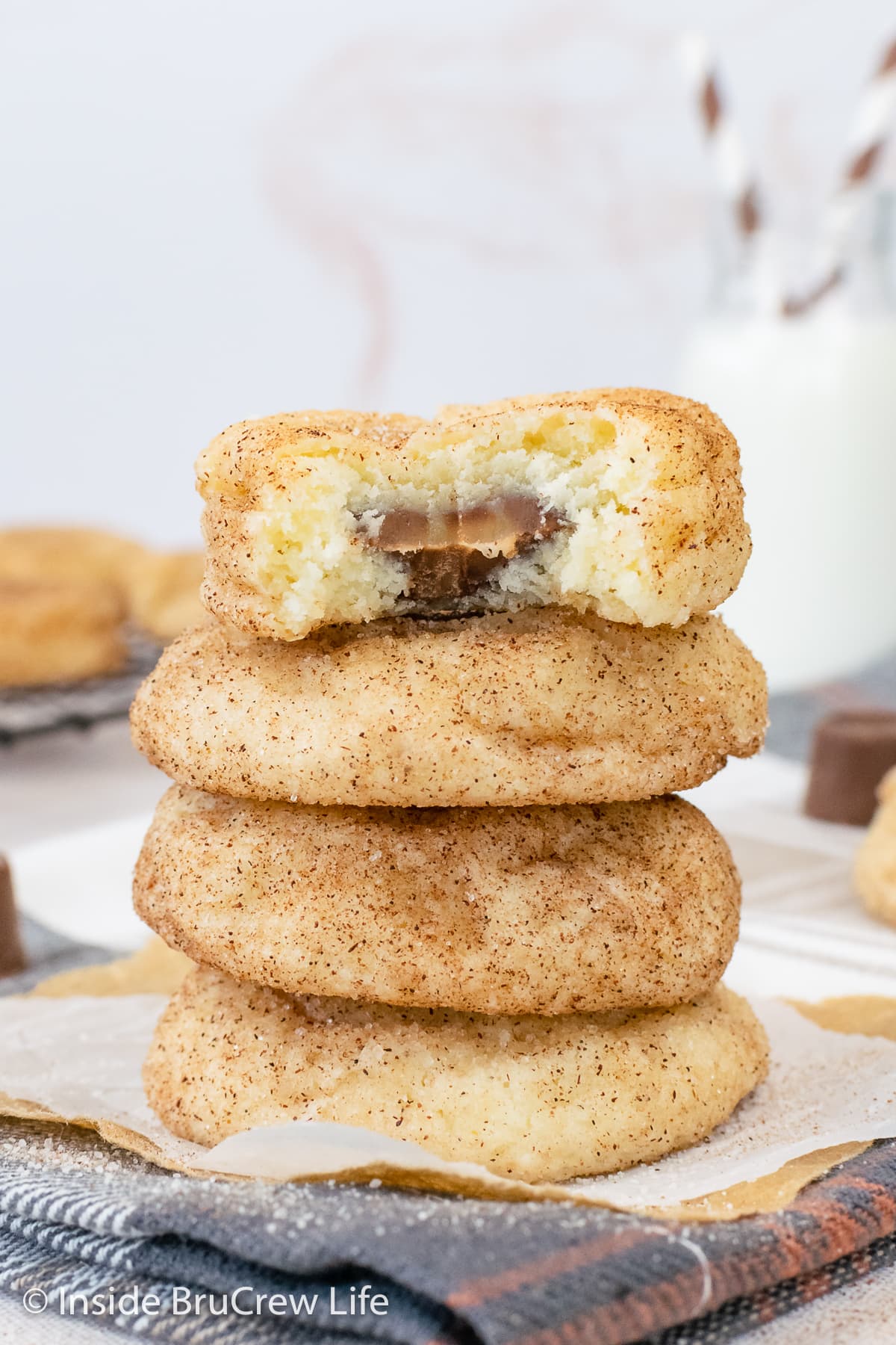 A stack of cinnamon sugar cookies stuffed with caramel candies on a towel.