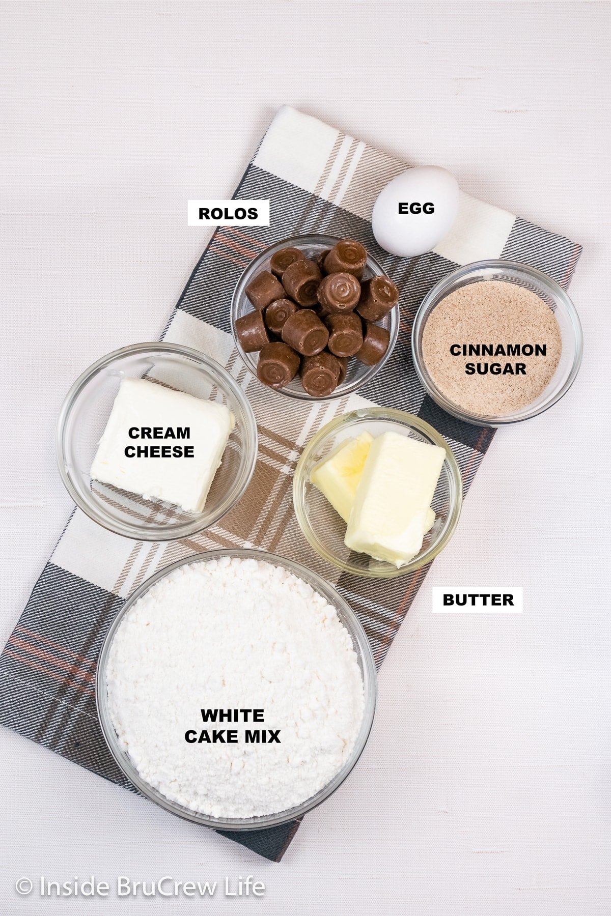 A white board with bowls of ingredients needed to make cinnamon cake mix cookies.