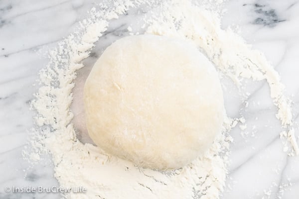 A marble board with a ball of homemade sweet dough on it.