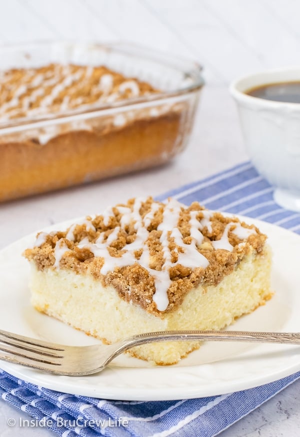 A white plate with a square of glazed brown sugar coffee cake on it.