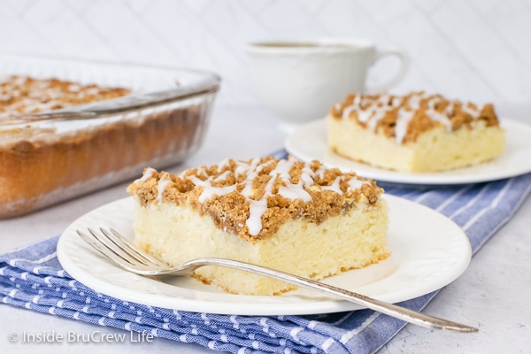 Two white plates with squares of coffee cake with brown sugar crumbles and glaze.