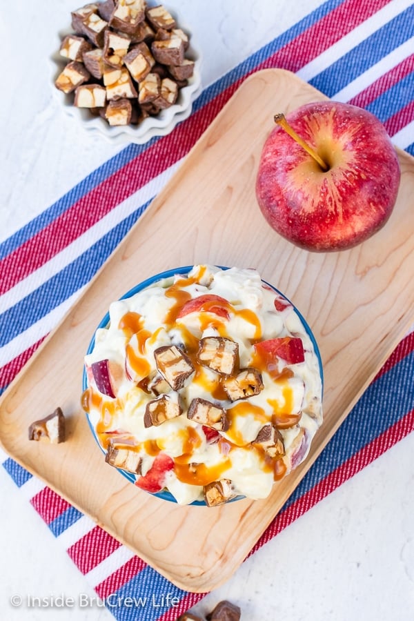 Overhead picture of a bowl filled with Snickers salad and drizzled with caramel ice cream topping.