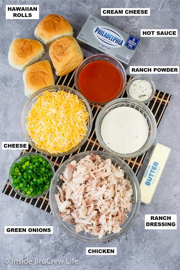 A gray board with bowls of ingredients on it needed to make buffalo chicken slider sandwiches.