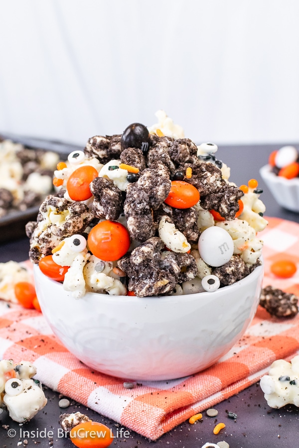 A white bowl filled with white chocolate Oreo popcorn with Halloween M&M candies.