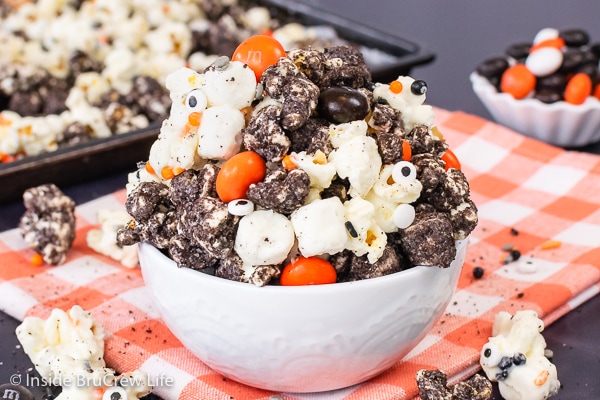 A white bowl filled with cookies and cream halloween popcorn loaded with holiday candies and sprinkles.