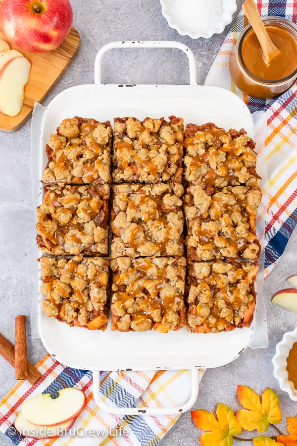 A white tray with squares of salted caramel apple pie bars lined up on it.