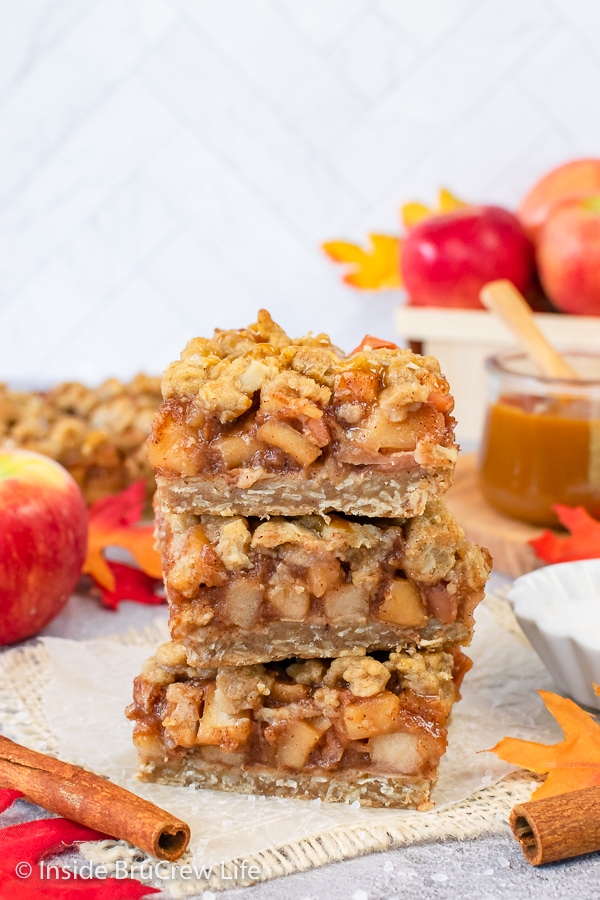 A stack of three apple pie bars on a piece of tan fabric.