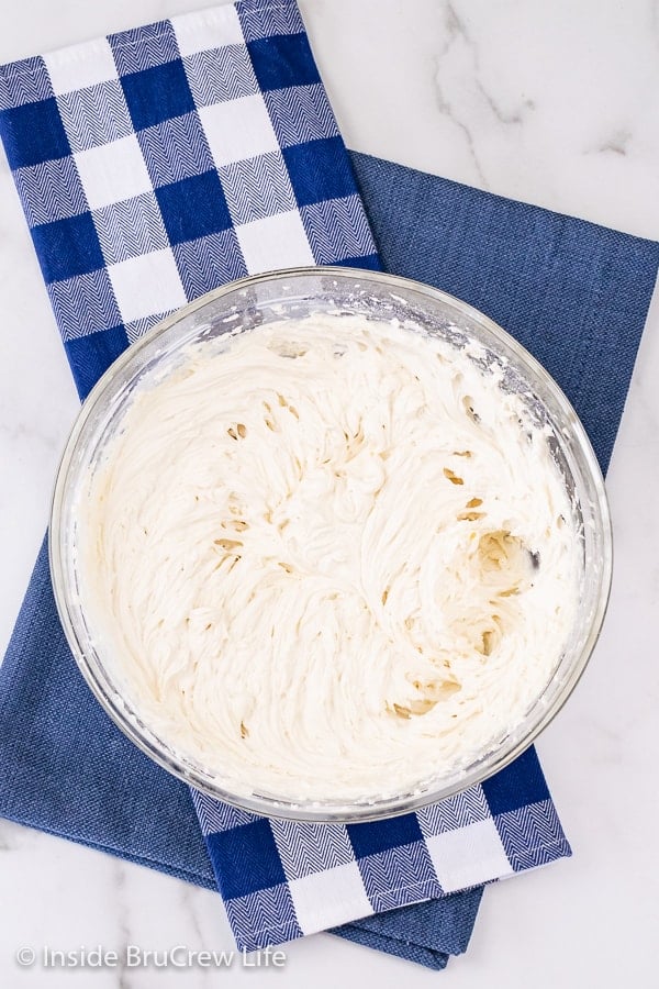 An overhead picture of a large bowl of vanilla buttercream on a blue towel.