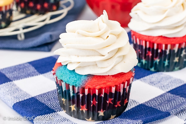 A cupcake topped with a swirl of vanilla buttercream on a blue and white towel.