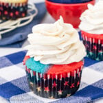 A blue and red cupcake topped with a swirl of vanilla frosting.