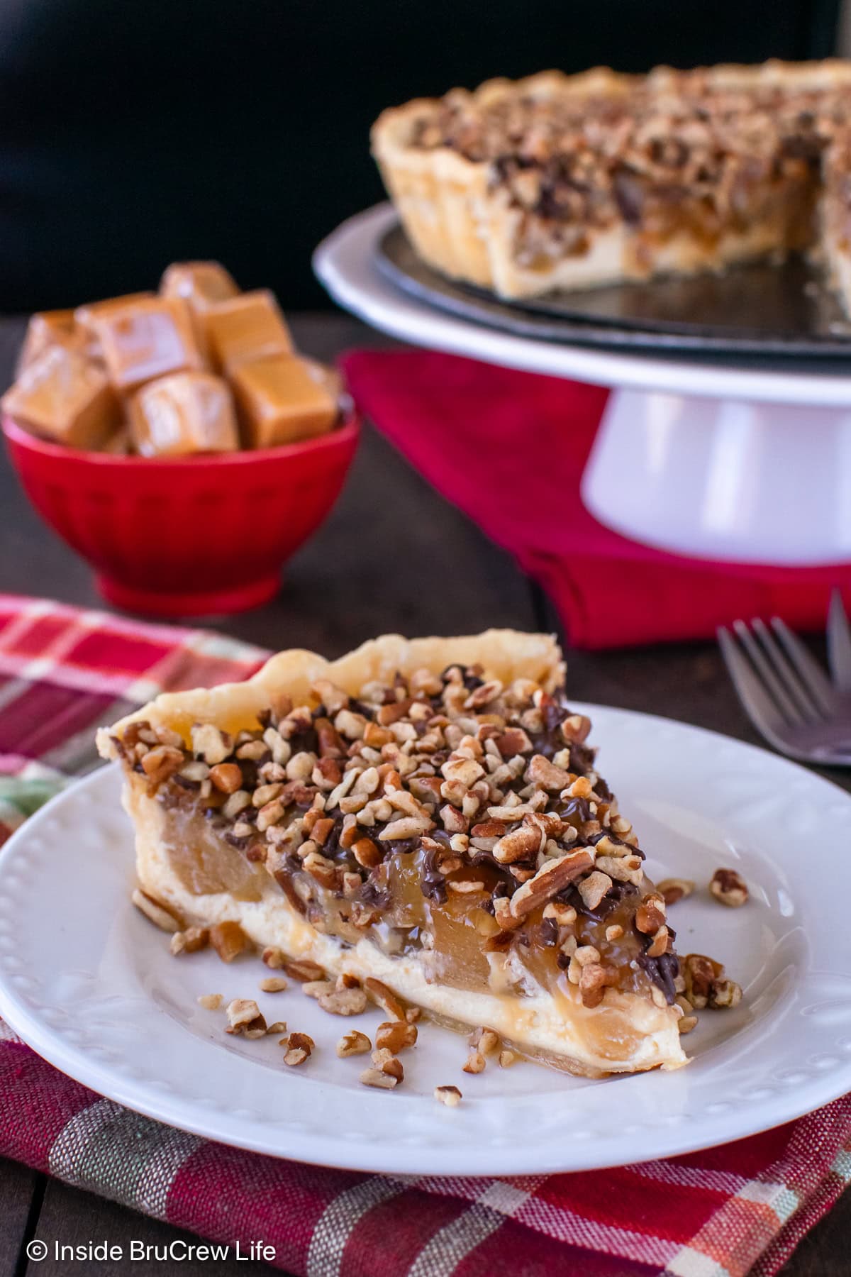 A slice of cream cheese apple tart topped with pecans and caramel.