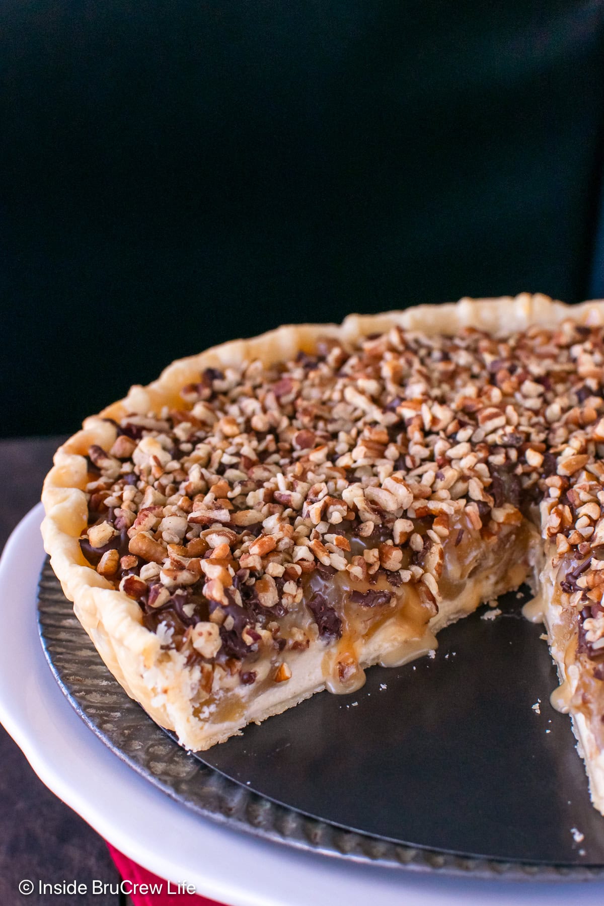 An apple turtle tart on a white cake stand.