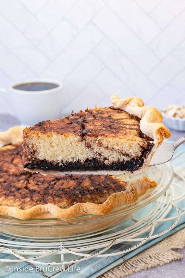 A glass pie plate with a funny cake in it and a spatula lifting a slice out.