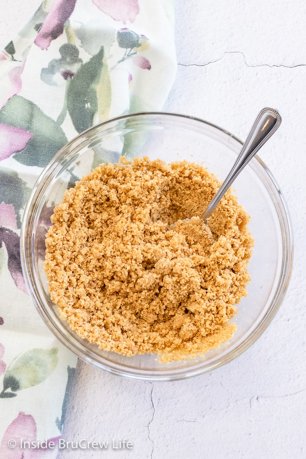 Overhead picture of a glass bowl filled with a graham cracker pie crust mixture.