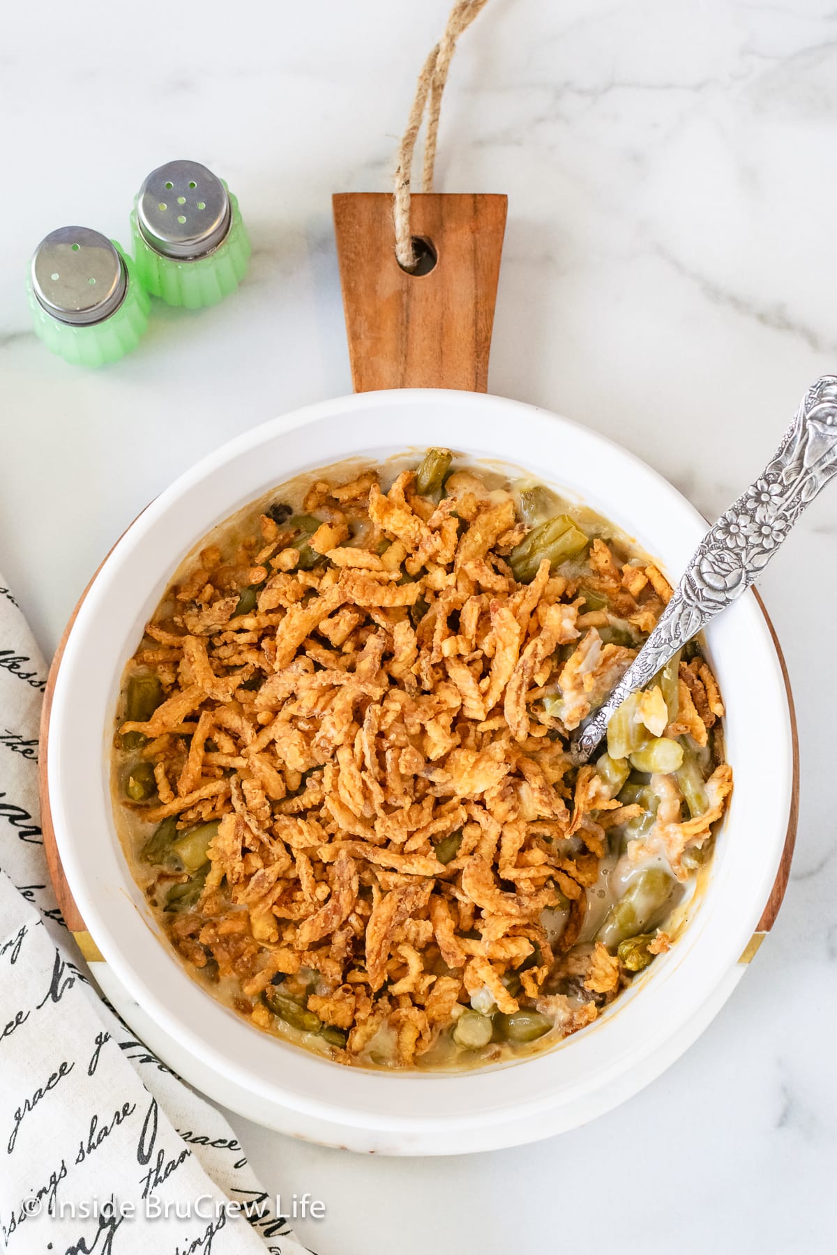 A white bowl with a casserole and a spoon in it.