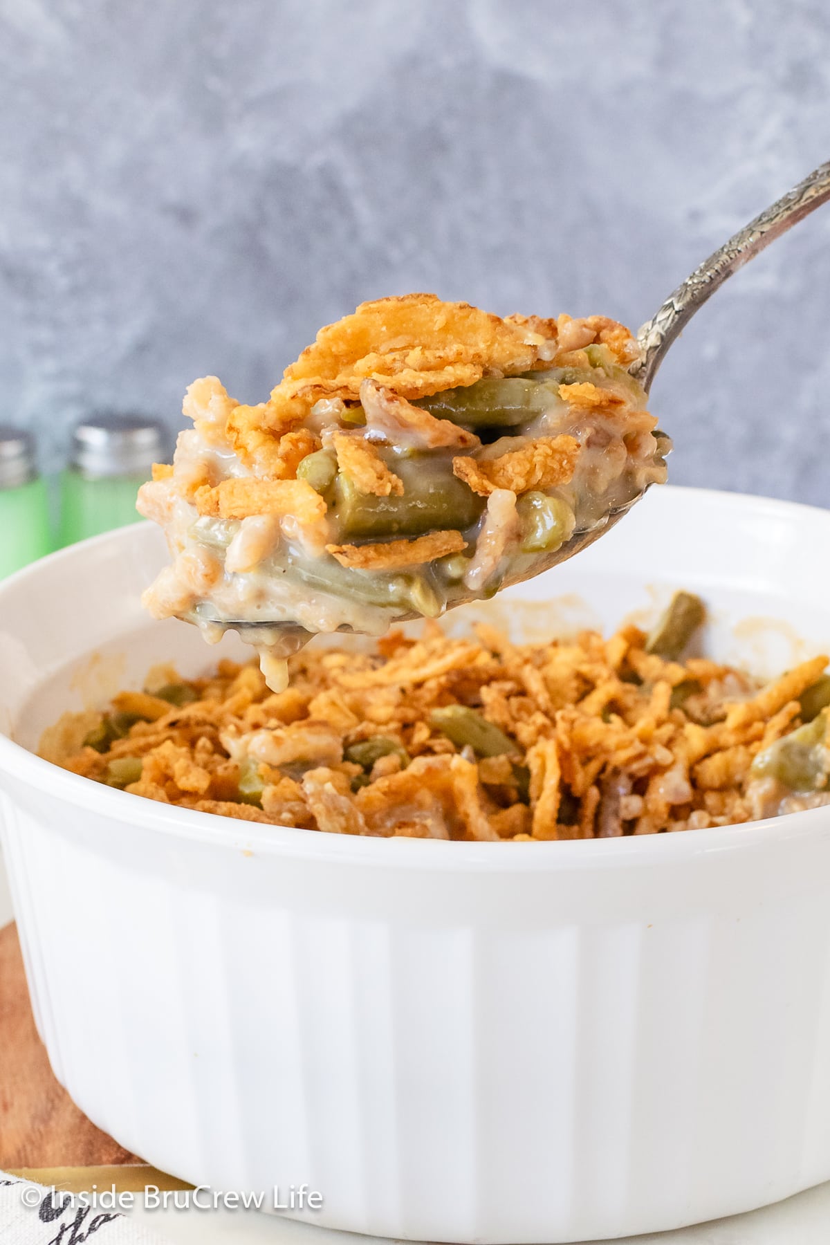 A spoon lifting green beans and french fried onions out of a dish.