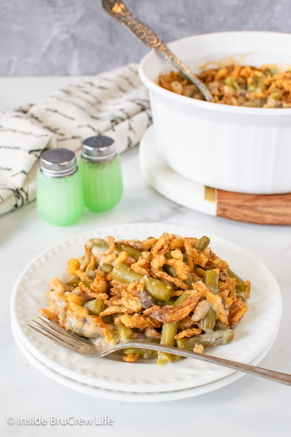 A white plate with a helping of green bean casserole on it.