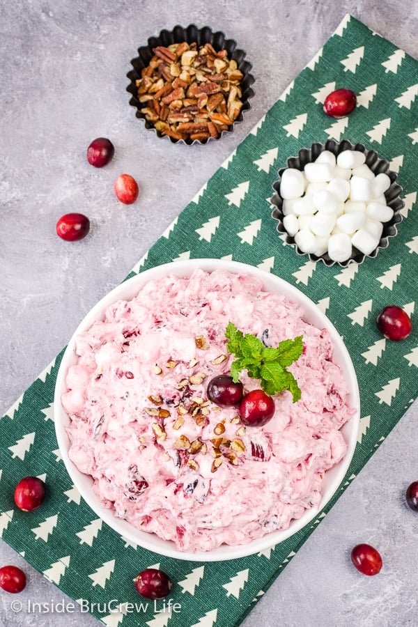 A white bowl filled with pink cranberry fluff sitting on a green and white towel.