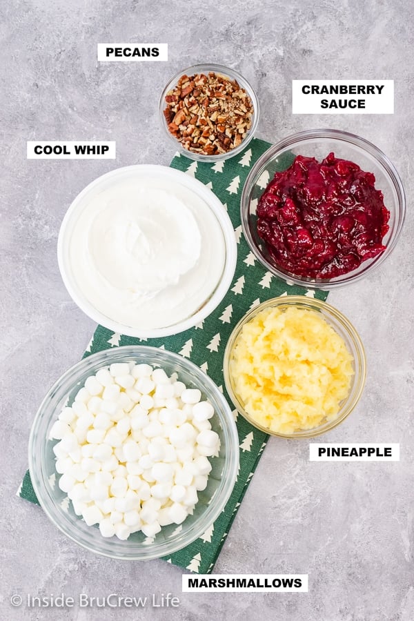 An overhead picture of a gray board with bowls of ingredients needed to make cranberry fluff.