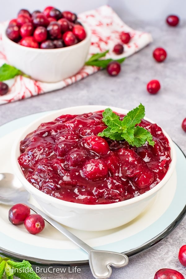A white bowl filled with homemade cranberry sauce topped with mint leaves.