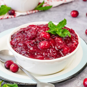 A white bowl filled with homemade whole berry cranberry sauce topped with mint leaves.