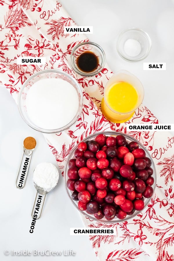 A white board with bowls of ingredients needed to make a homemade cranberry sauce.