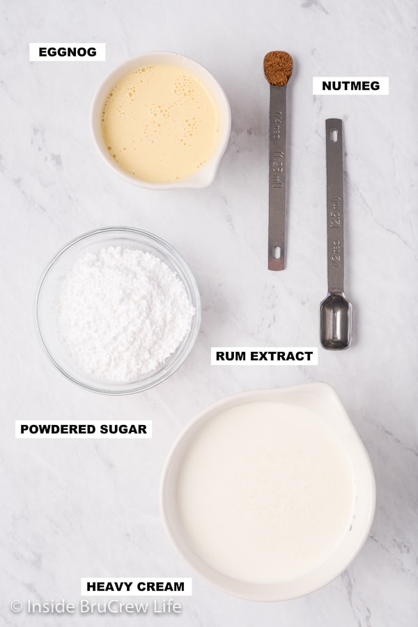 An overhead picture of a white board with bowls filled with ingredients needed to make eggnog whipped cream.