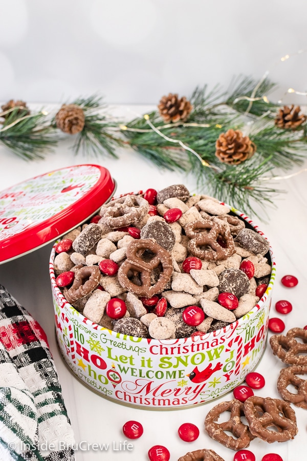 A Christmas tin filled with reindeer munch made with chocolate covered pretzels and red M&M's.