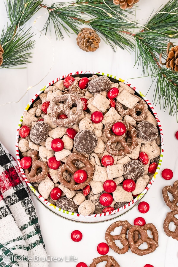 Overhead picture of a tin filled with Reindeer munch mix made with M&M's and chocolate covered pretzels.