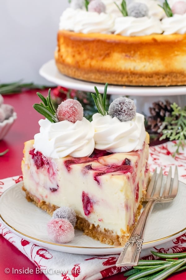 A white plate with a slice of White Chocolate with swirls of cranberry sauce in it. Great cheesecake recipe to make for the holidays.