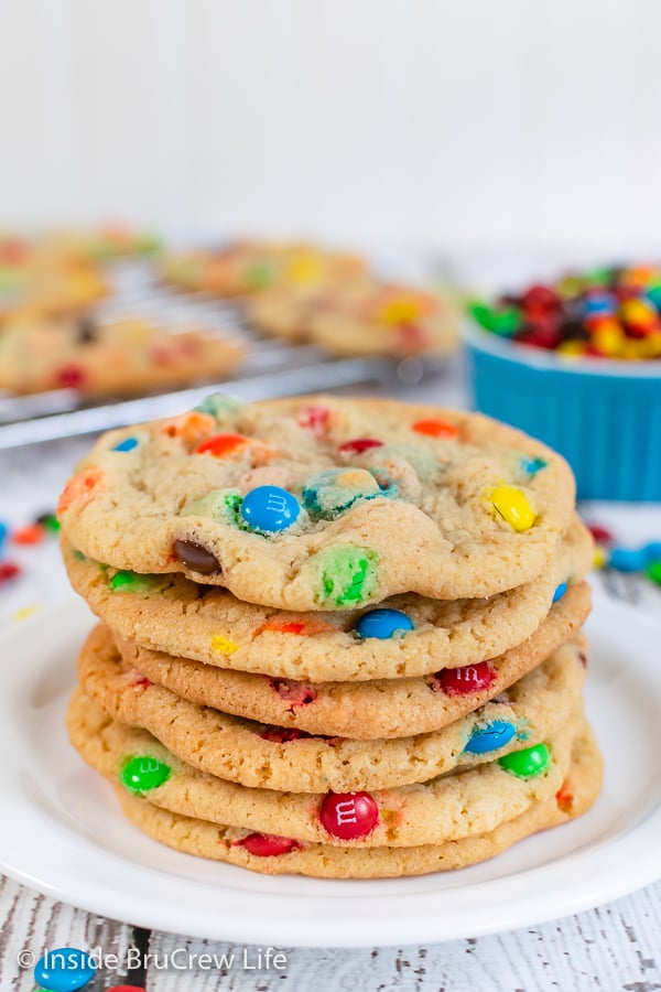 A white plate with a stack of thin chewy cookies with M&M's in them.