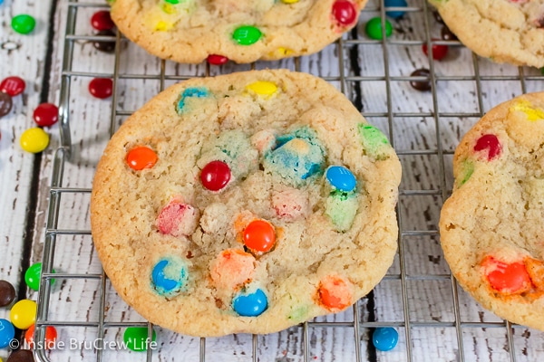 A wire rack with thin M&M cookies on it.