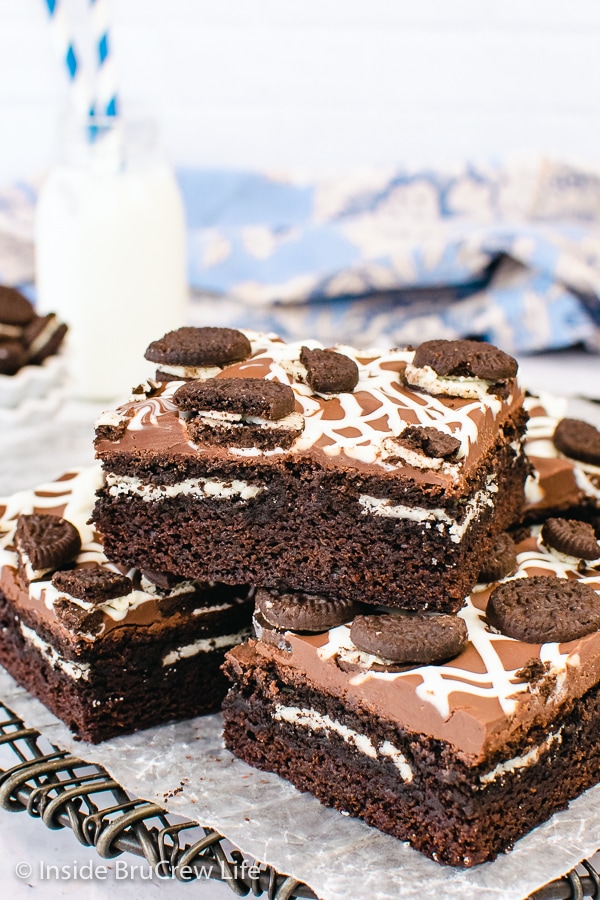 A stack of homemade chocolate brownies made with Oreo cookies on a black wire rack.