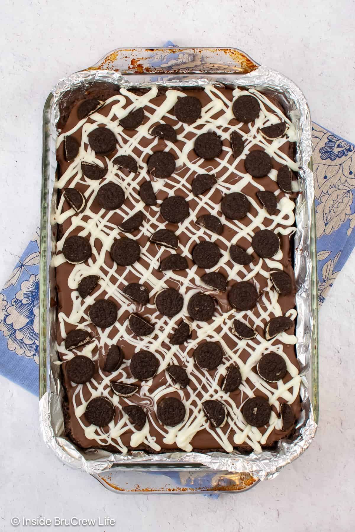 A pan of brownies topped with chocolate and mini Oreo cookies.