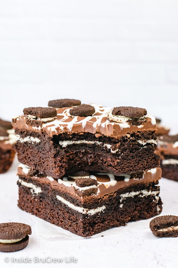 Two Oreo stuffed brownies stacked on top of each other with a bite taken out of the top one.