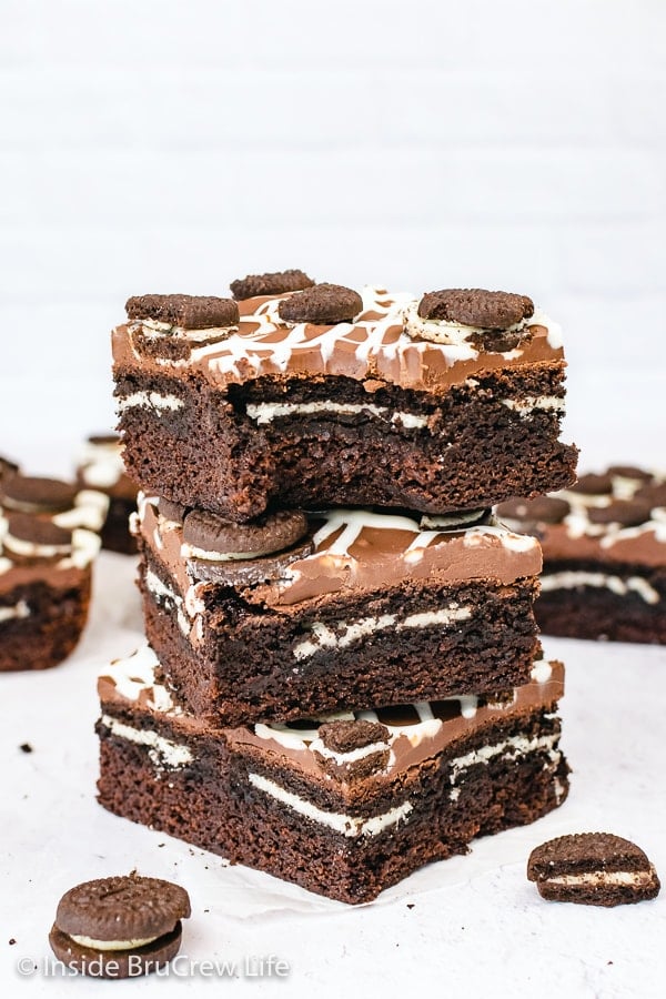 Three Oreo brownies stacked on top of each other with a bite out of the top one showing the hidden Oreo cookie inside.